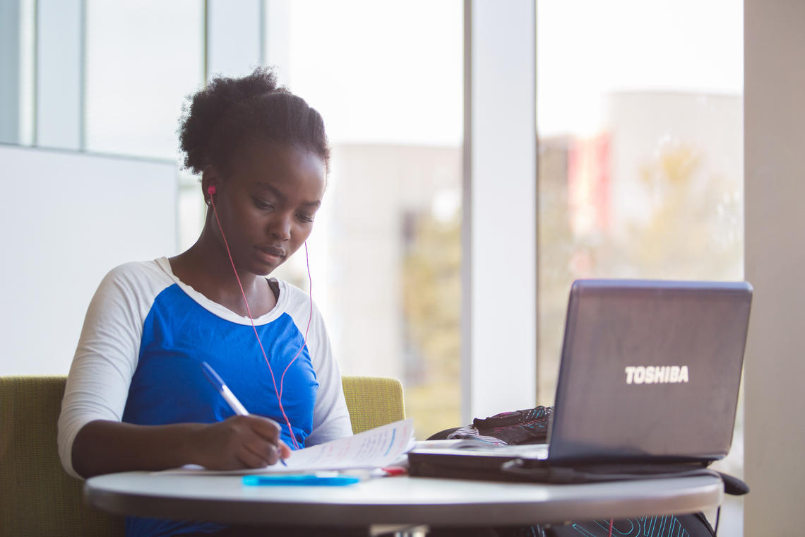 young woman works on a laptop in the library