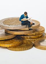 person who is reading a book while sitting on a stack of coins